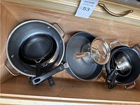 Drawer with assorted pots and pans including non-stick frying pans, aluminum large pot, and small saucepan.