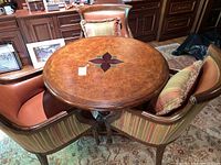 Three upholstered armchairs arranged around round wooden table showing full set