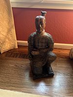 Front view of kneeling soldier statue showing armor details and facial features