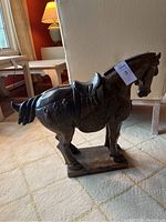 Full side view of the carved stone horse statue on carpeted floor