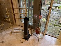 Wide view showing gold-tone towel rack, small glass shelf, and electric heater in front of a glass door.