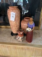 Photo showing both stone/marble vases with decorative figurines placed in front, tagged with lot number
