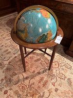 World globe on wooden tripod stand showing map details and overall condition.