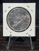 Front side of the 1966 Canadian silver dollar coin showing the canoe design with two paddlers, denomination and year 1966.