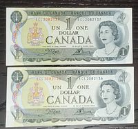 Two 1973 Canadian one dollar bills laid flat showing both front sides with consecutive serial numbers ECL2082136 and ECL2082137.
