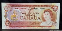 Front of 1974 Canadian $2 banknote showing Queen Elizabeth II portrait, serial number AGM5303479, and Canadian Coat of Arms.