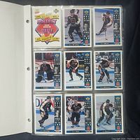 White 3-ring binder with hockey cards in clear 9-pocket Ultra Pro sleeves, showing 9 cards per page including player images, McDonald's logo, and NHL All Star branding.