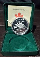 Reverse side of the coin showing National Ballet dancers design, encapsulated in plastic, seated in green velvet display case with certificate insert