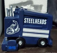 Close-up of the Zamboni model showing dark blue body with 'Steelheads' text and logo in white, wheels and detailing visible.