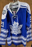 Front view of blue Toronto Maple Leafs Winter Classic jersey size 50 showing large white maple leaf logo and #21 with signatures on front.