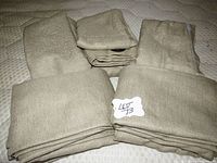 Folded green curtains stacked showing fabric texture and multiple curtains in lot.