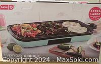 Photo of the Dash Everyday Griddle box showing the extra large griddle surface with ribbed and flat cooking zones and temperature control knob.