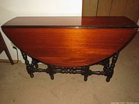 Table folded with leaves down, showing exterior solid mahogany wood surface and turned legs.
