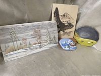 Four hand painted art pieces including winter snow scene on marble tile, mountain snow scene rock, eagle drawing tile, and painted geode slice