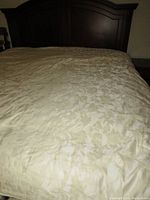 Comforter fully spread on king size bed showing ivory damask pattern.