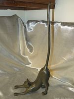 Side angle of black cast iron cat stretching with tall tail, showing overall shape and detail of the figure.