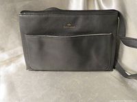 Front view showing the black pebbled leather wristlet with an outside pocket and gold Juicy Couture logo.