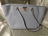 Front view of light grey Michael Kors travel tote with double shoulder straps and gold-tone front lock detail