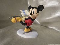 Front and side view of the Mickey Mouse skating figurine showing the detailed colorful sculpture and skating pose on a white base.
