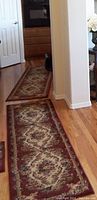 Photo showing two matching length floor runners in a hallway with intricate burgundy and beige pattern.
