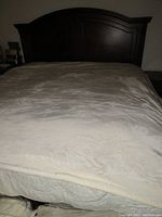Full view of the king size blanket on bed showing smooth velvet cream-colored surface.