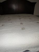 Photo shows king size quilt spread on bed with visible floral embroidery and quilted texture.