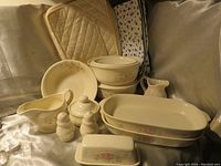 Photo showing full set of vintage Pfaltzgraff Tea Rose ceramic serveware items on silver fabric draping, including serving pans, butter dish, salt and pepper shakers, covered bowls, large bowl, sugar bowl, and creamer.