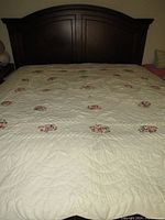 Full view of the king size quilt spread on the bed showing off the overall design and floral embroidery pattern.