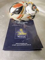 Photo of sleeping calico cat ceramic figurine showing handpainted multicolor design with gold glaze.