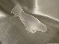 Frosted glass bird sculpture viewed from side angle showing full body, textured wings, and fanned tail.