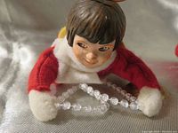 Close-up of Megan angel's face, red and white outfit, and clear bead necklace.