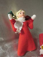 Front view of the Simpich angel figurine named Heather, showing the red dress, white scarf, blonde hair, and held bell and violin details.