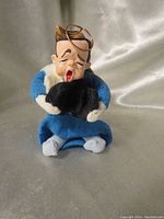 Front view of the Simpich Patrick angel ornament showing blue gown, black book, facial expression and striped socks.