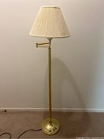 Full view of the brass floor lamp showing the pleated shade and articulating arm.