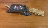 View of hand carved wooden turtle doorstop showing top and side with wood wedge for doorstop function