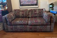 Full front view of loveseat sofa showing geometric patterned upholstery and two seat cushions with two back cushions.
