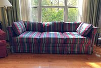 Front view of striped sofa showing three seat cushions and two arm cushions with striped fabric in blue, green, and deep red.