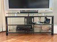 Front view of metal and glass TV stand with Sony TV and media devices