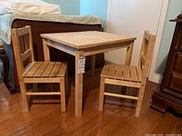 Front view of the pine children's table flanked by two matching pine chairs in a bedroom setting.