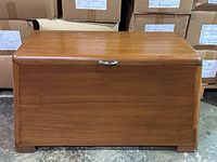 Wooden blanket box photographed front-facing, showing mid century style and metal handle.