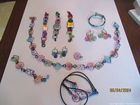 Full lot layout showing all anodized aluminum jewelry pieces including watches, necklace, earrings, bracelet, and eyeglass cord with colorful spiral and geometric wire designs.