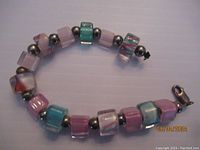 Bracelet with square pastel art glass beads and sterling silver spacer beads laid out flat showing clasp.