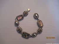 Full view of the silver tone artisan magnetic bracelet laid flat showing rectangular and oval segments with beaded and floral detailing.