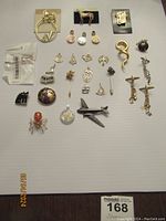 Photo showing the entire assortment of charms, pins, and brooches arranged on white surface.
