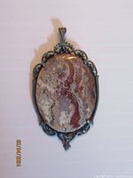 Front view of the oval Crazy Lace Agate pendant in sterling silver with detailed filigree.