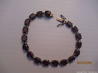 Full view of garnet and sterling silver bracelet laid flat in a circle, showing the linked garnet stones and clasp.