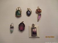 Overview of all six gemstone pendants arranged on flat surface showing various stones and wire wraps