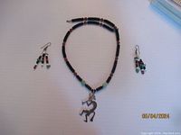 Photo showing entire Kokopelli necklace with matching earrings laid out on a plain surface.