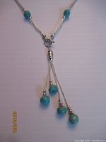 Close up of the bottom lariat drop showing the sterling silver liquid strands and turquoise beads.