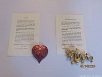 Both brooches with their identification cards from The Metropolitan Museum of Art, showing materials and signatures.
